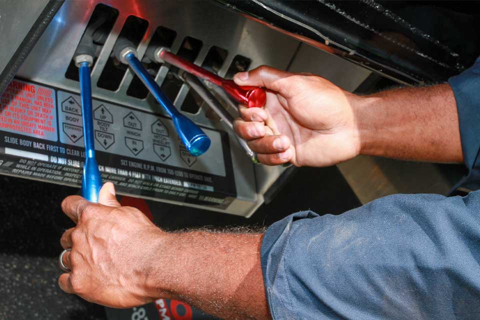 Hands of tow truck driver operating bed and winch levers
